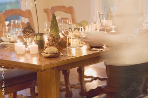 Photo: Woman bringing plates to table laid for Christmas Woman bringing plates to table laid for Christmas