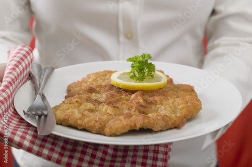 Photo: Woman holding plate of Wiener schnitzel (veal escalope) Woman holding plate of Wiener schnitzel (veal escalope)