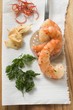 Garlic prawns on slotted spoon, ingredients beside it