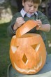 Small boy putting lid on pumpkin lantern