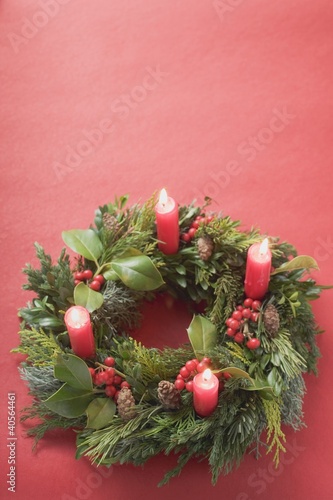 Photo: Advent wreath with four burning candles on red background Advent wreath with four burning candles on red background