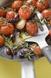 Fried cherry tomatoes with garlic and olives in frying pan