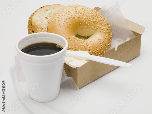 Photo: Sesame bagel with crème fraîche in cardboard box, cup of coffee Sesame bagel with crème fraîche in cardboard box, cup of coffee