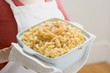 Photo: Woman holding baking dish of macaroni cheese Woman holding baking dish of macaroni cheese