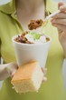 Woman holding chili con carne in paper cup and cornbread