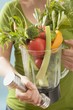 Woman holding hand weight & fresh vegetables in liquidiser