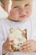 Baby holding a partly-eaten slice of bread and butter