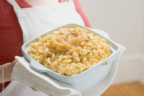 Photo: Woman holding baking dish of macaroni cheese Woman holding baking dish of macaroni cheese