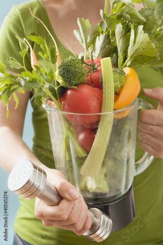 Photo: Woman holding hand weight & fresh vegetables in liquidiser Woman holding hand weight & fresh vegetables in liquidiser