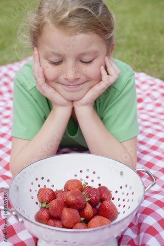Photo: Girl looking at strawberries in colander Girl looking at strawberries in colander