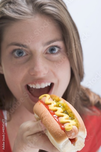 Foto: Woman eating a hot dog with mustard Woman eating a hot dog with mustard