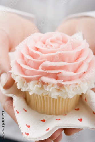 Foto: Hands holding cupcake with marzipan rose Hands holding cupcake with marzipan rose