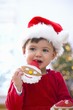 Foto: Little girl in Santa hat eating a biscuit Little girl in Santa hat eating a biscuit