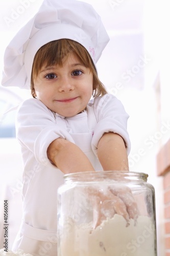 Foto: Little girl taking flour out of jar with both hands Little girl taking flour out of jar with both hands