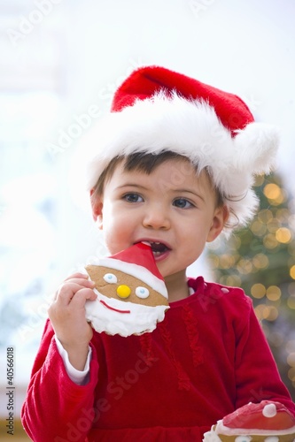 Foto: Little girl in Santa hat eating a biscuit Little girl in Santa hat eating a biscuit