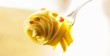 Egg tagliatelle with peas, ham and cream sauce on fork