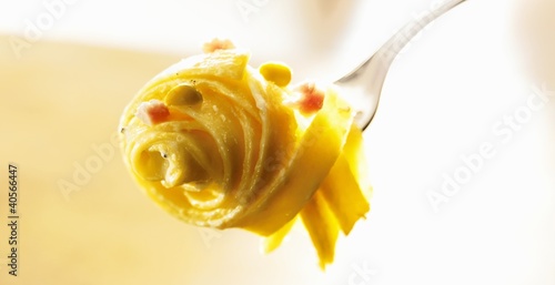 Photo: Egg tagliatelle with peas, ham and cream sauce on fork Egg tagliatelle with peas, ham and cream sauce on fork