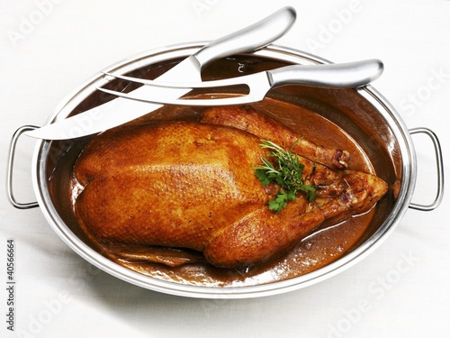 Photo: Roast goose in roasting dish, carving knife and fork Roast goose in roasting dish, carving knife and fork