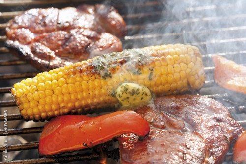 Foto: Corn on the cob with herb butter, pork steaks & pepper on barbecue Corn on the cob with herb butter, pork steaks & pepper on barbecue