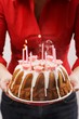 Woman holding iced ring cake with birthday candles