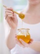 Young woman holding jar of honey and honey dipper