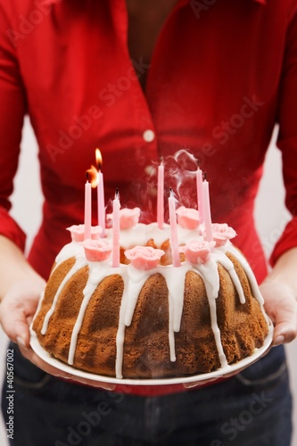 Photo: Woman holding iced ring cake with birthday candles Woman holding iced ring cake with birthday candles