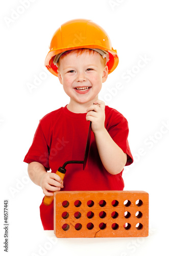 Photo: Builder boy or kid in red tshirt and hard hat. Construction conc Builder boy or kid in red tshirt and hard hat. Construction conc