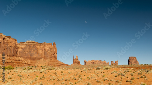 Photo: monument valley at dreamy summer day and moon with deep blue sky monument valley at dreamy summer day and moon with deep blue sky