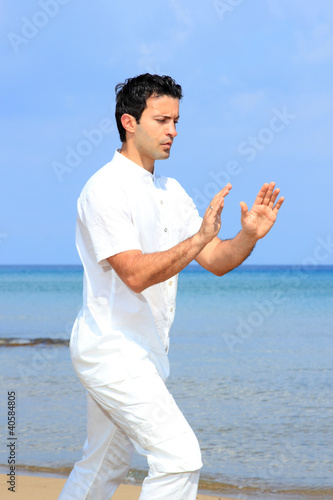 Photo: Handsome man on the beach meditating Handsome man on the beach meditating