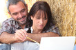 Farming couple sat with laptop computer