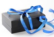 black gift box with a blue ribbon on a white background