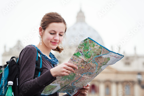 Photo: Pretty young female tourist studying a map at St. Peter's square Pretty young female tourist studying a map at St. Peter's square