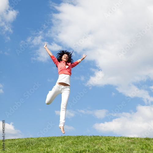 Foto: pretty young woman jumping on green grass pretty young woman jumping on green grass