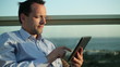 Businessman sitting outdoors and using tablet computer