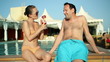 Young couple drinking exotic cocktails by the pool