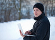 Foto: junger Mann mit Laptop im Schnee junger Mann mit Laptop im Schnee
