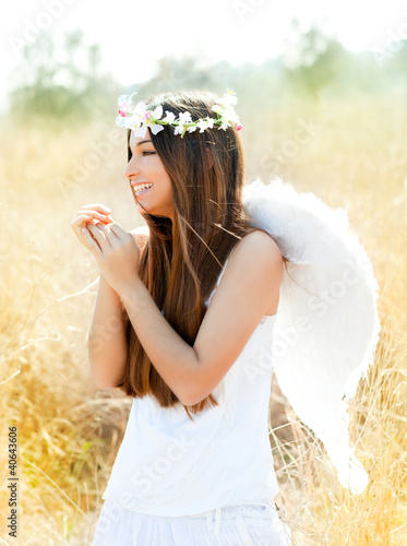 Foto: Angel girl in golden field with feather white wings Angel girl in golden field with feather white wings