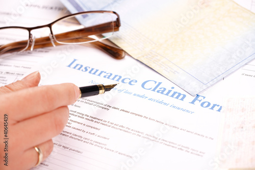 Photo: hand filling in insurance claim form hand filling in insurance claim form