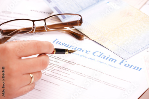 Photo: hand filling in insurance claim form hand filling in insurance claim form