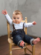 Baby sitzt auf einem Stuhl und winkt Baby sitzt auf einem Stuhl und winkt