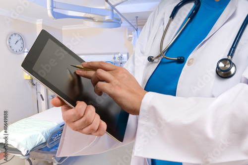 Photo: Doctor pointing on tablet PC at emergency room Doctor pointing on tablet PC at emergency room