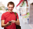 portrait of young man touching mobile screen at street