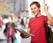 portrait of handsome student holding notebook and pen at crowded