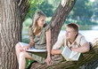Young guy and girl with books on the nature near lake Young guy and girl with books on the nature near lake