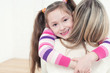 Cute girl embracing her mom, smiling and looking at camera