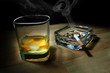 ashtray full of butts and glass of whiskey