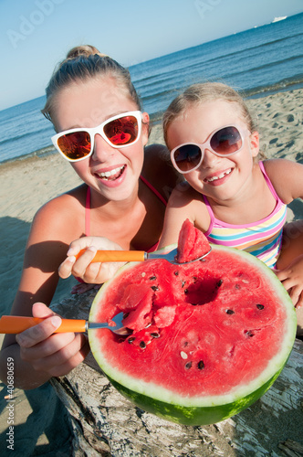 Photo: Happy summer - girls eating watermelon on the beach Happy summer - girls eating watermelon on the beach