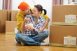 Young couple among boxes putting coin in piggy bank