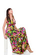 Woman in a bright summer dress posing against white background