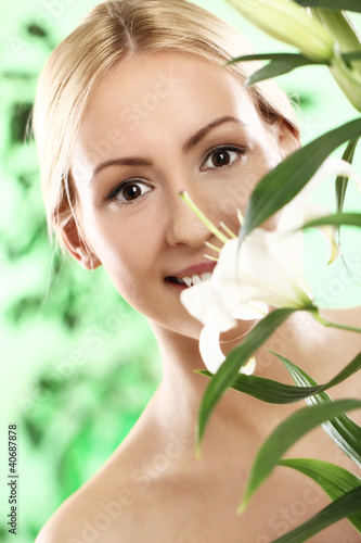 Photo: Young woman looking through green leaves Young woman looking through green leaves